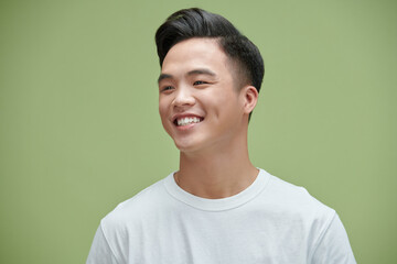 Portrait shot of young adult Asian man smiling posturing on green wall background - Powered by Adobe