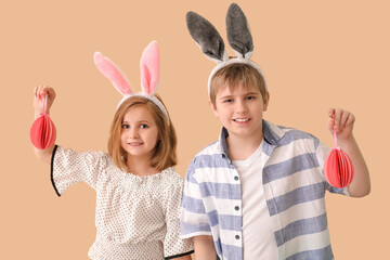 Little children in bunny ears with paper Easter eggs on beige background