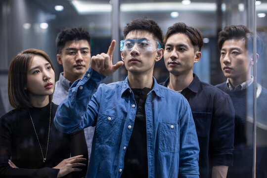 Confident Chinese designers checking futuristic glasses