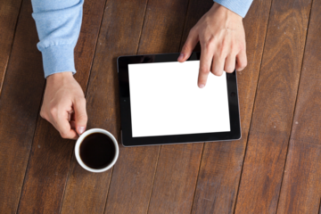 Man using digital tablet while having cup of coffee