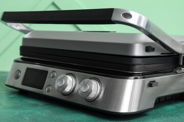 Modern electric grill with closed lid on green table