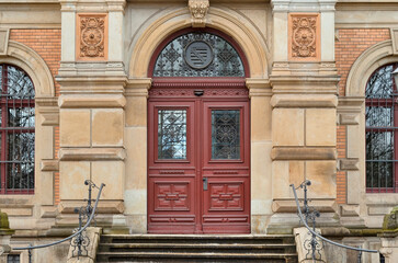 View of old building with red wooden door and steps