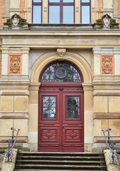 View of old building with red wooden door and steps