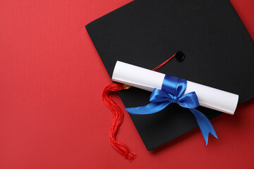 Diploma with blue ribbon and graduation hat on background