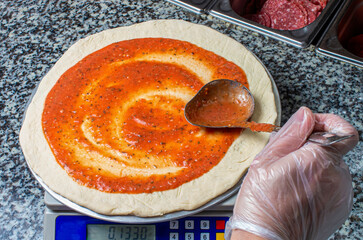 Pizza cooking by the chef, tomato sauce smears on the dough