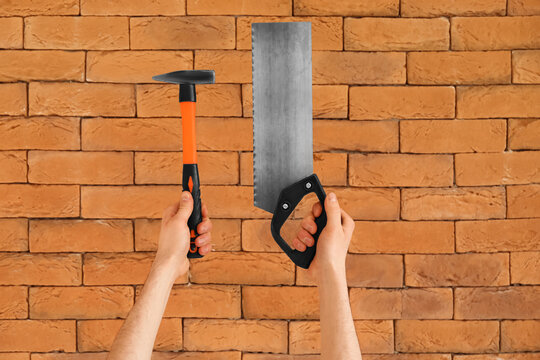 Worker with hammer and handsaw on brick background