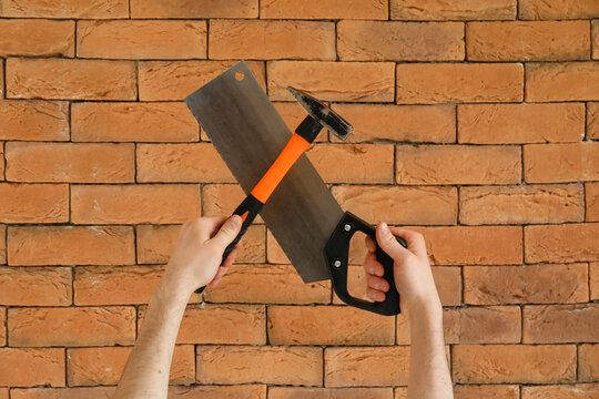 Worker with hammer and handsaw on brick background