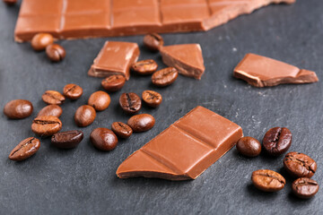 Tasty chocolate and coffee beans on dark background, closeup