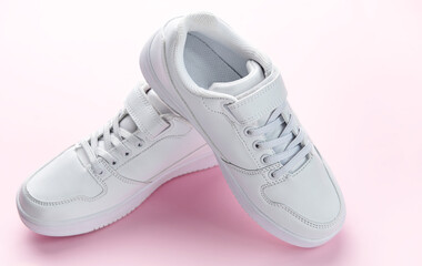 White sneakers on a pink background.