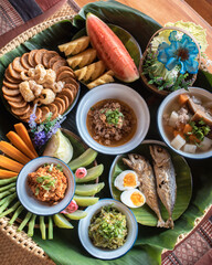Top View of Local Thai Food, Northern Thai food , Northern country style dinner (pork rind, Fried Pork Sausage, Nam Prik Ong, Nam Prik Num, fried mackerel, boiled eggs, Pork Soup and Fruit)