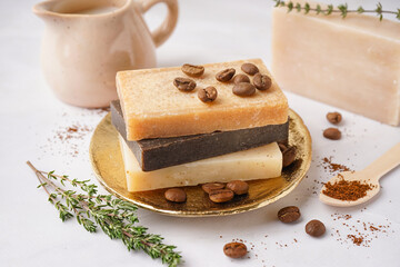 Plate with natural soap bars, coffee beans and thyme on light table