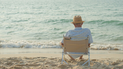 elderly men sit at the beach watching the sun and the sea on their summer vacation and they smile...