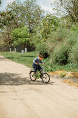 Naklejka premium Happy child riding his bike outside his home. Young boy learning to ride his bicycle. Portrait little boy enjoy having fun riding exercise bike. Child first bike. Kid outdoors sport summer activities