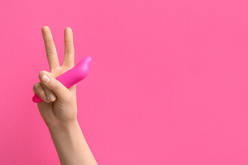 Woman with vacuum vibrator showing victory gesture on pink background