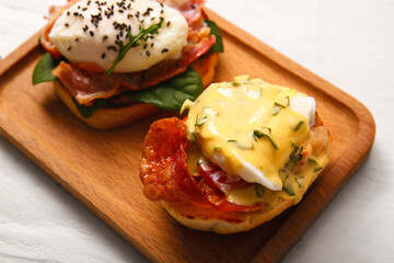 Board with delicious eggs Benedict on white wooden table, closeup