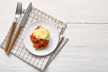 Plate with tasty egg Benedict on white wooden table
