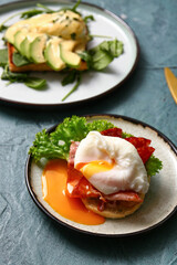 Plates with tasty eggs Benedict on grey grunge table, closeup
