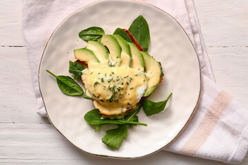 Plate with tasty egg Benedict on white wooden table