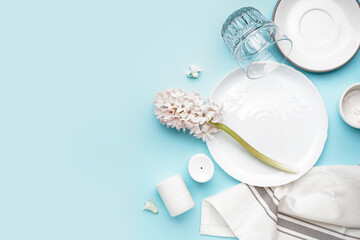 Composition with clean plates and beautiful hyacinth flower on blue background