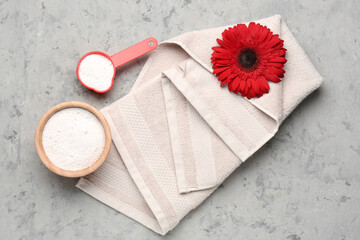 Laundry detergents, gerbera flower and towel on grey grunge background