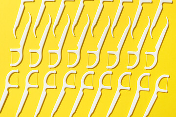 Many floss toothpicks on yellow background