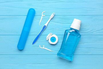 Dental floss, rinse, toothpicks and brush on blue wooden background