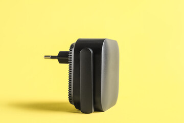 Black WiFi repeater on yellow background