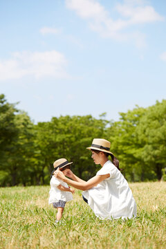 芝生の上でお揃いの帽子を被る母と娘