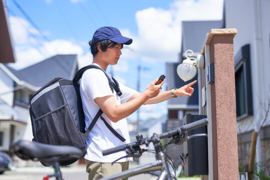 家のチャイムを押すフードデリバリーの配達員