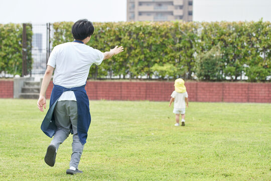 芝生で子供を追いかける男性の保育士