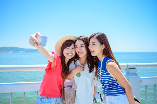 海の上の橋で写真を撮るリゾートへ旅する女性3人