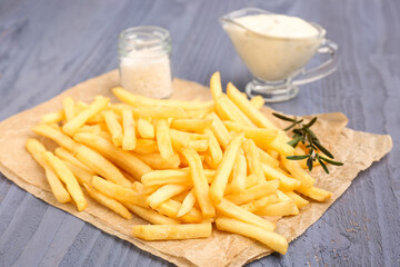 Tasty french fries, salt and mayonnaise on blue wooden background