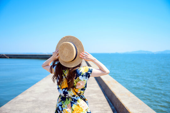 港の防波堤を歩く海のリゾートへ旅する女性
