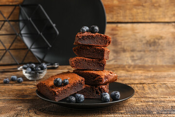 Plate with pieces of tasty chocolate brownie on wooden background