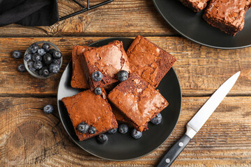 Plate with pieces of tasty chocolate brownie on wooden background