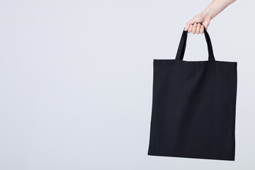 Hand of caucasian woman holding black canvas bag with copy space on white background