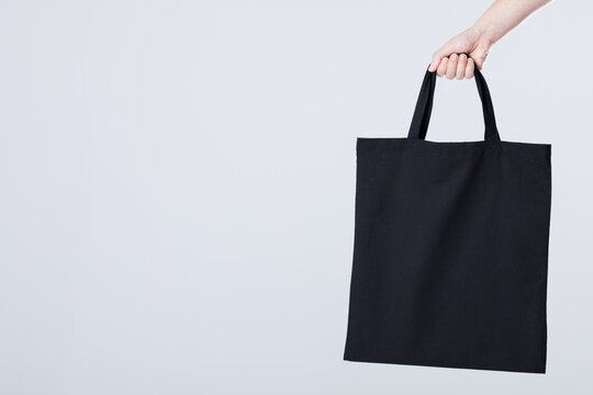 Hand Of Caucasian Woman Holding Black Canvas Bag With Copy Space On White Background