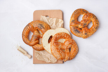 Wooden board with tasty pretzels on light background