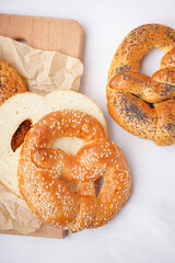 Wooden board with tasty pretzels on light background, closeup