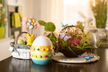 Easter theme. Easter decorations. Easter eggs in basket and easter bunny. Bouquet of spring flowers. Shining wooden brown table.