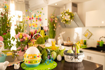 Easter theme. Easter decorations. Easter eggs in basket and easter bunny. Bouquet of spring flowers. Shining wooden brown table.