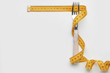 New measuring tape and fork on light background