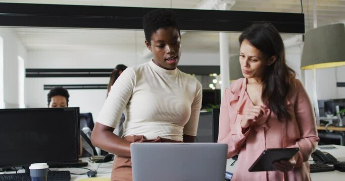 Focused diverse businesswomen working together on laptop in office