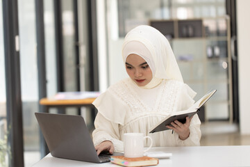 Happy Asian Muslim Woman working at desk in office, Businesswoman and education online concept. 