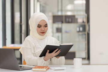 Happy Asian Muslim Woman working at desk in office, Businesswoman and education online concept. 