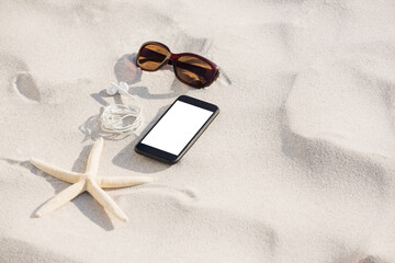 Starfish with sunglasses and mobile phone kept on sand