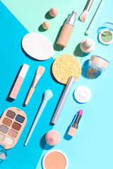 Decorative cosmetics with makeup brushes and sponges on color background