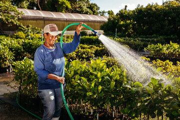 Black woman watering garden by day