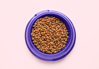 Bowl with dry pet food on pink background