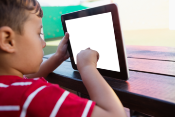 Close up of boy touching digital tablet while sitting at table